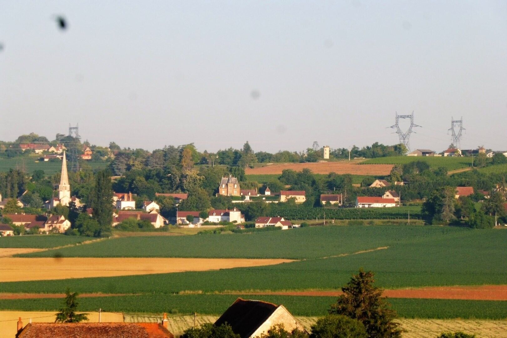 Un paisaje rural con casas, una iglesia y líneas eléctricas.