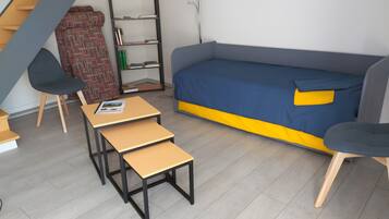 A compact living space with a sofa, a small table, a chair, a bookshelf, and a patterned rug.