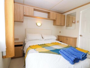 Un dormitorio con una cama, armarios de madera, un espejo y una lámpara fijada a la pared.