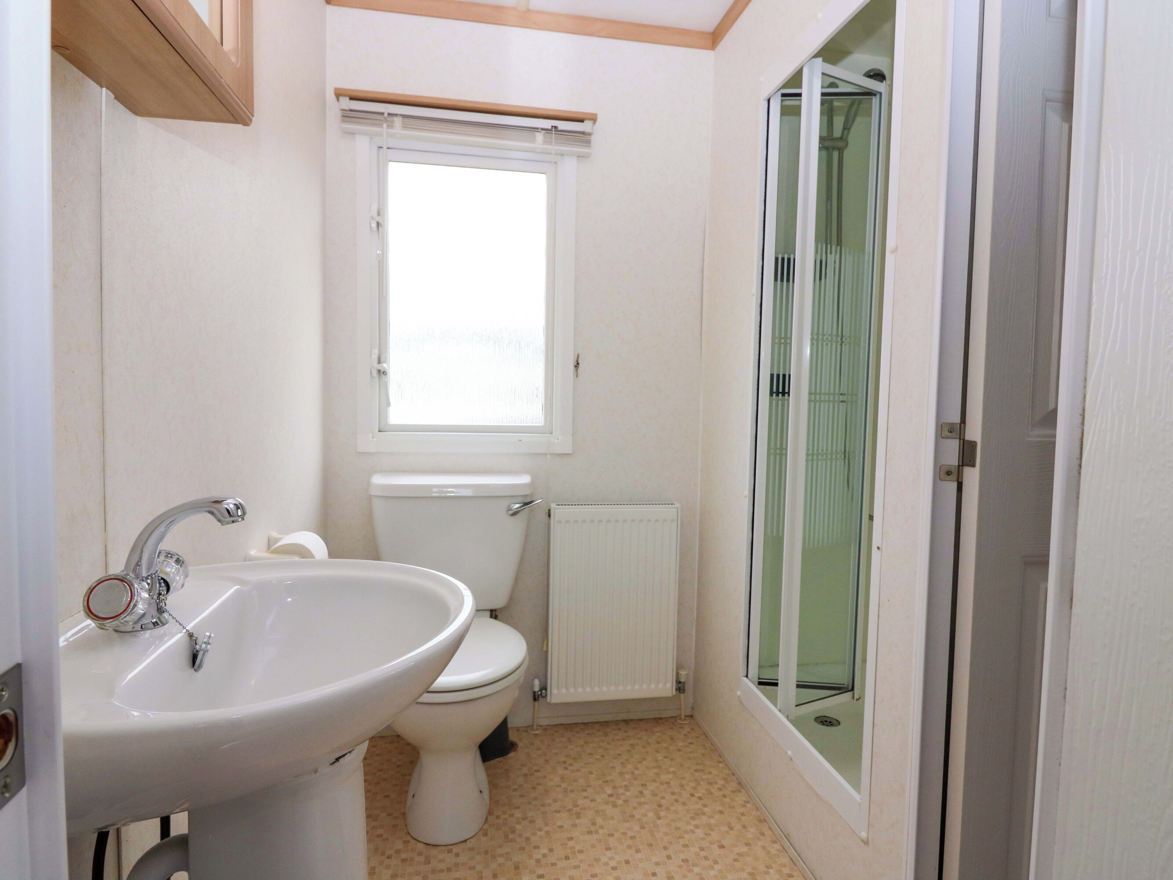 A bathroom with a sink, toilet, and a glass shower enclosure.