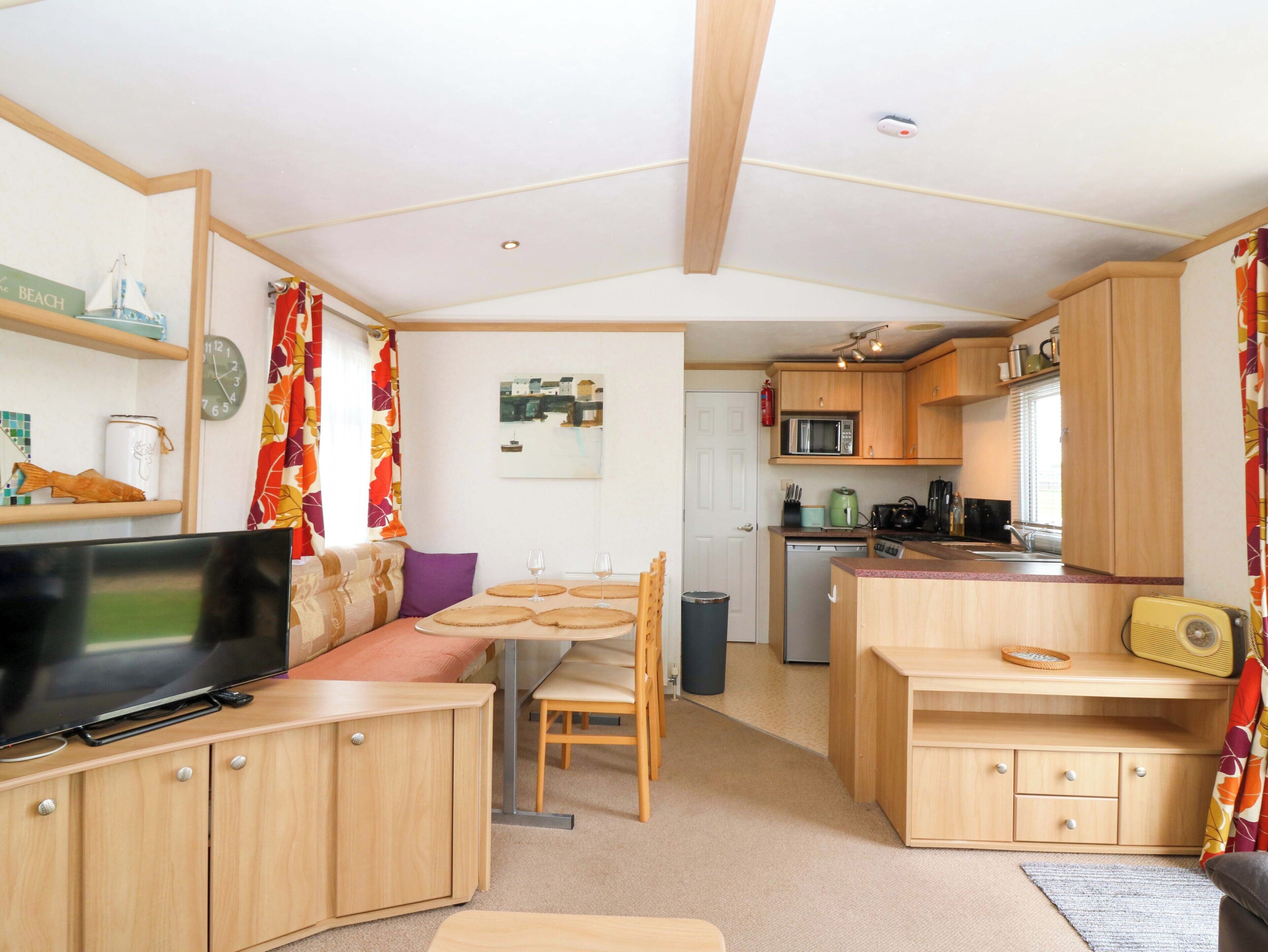 A compact living space with a kitchenette, a dining area, and a television.