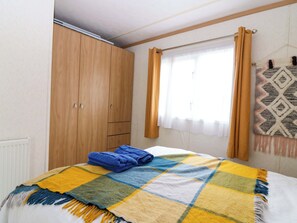 Quarto com cama, guarda-roupa, janela com cortinas e um painel de parede estampado.