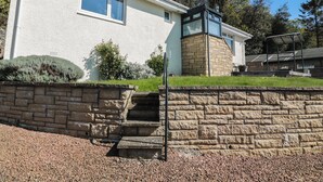 Ein modernes Haus mit Naturstein-Fassade, einem kleinen Vorgarten und einem gepflasterten Auffahrt.