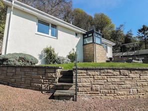 A modern house with a stone facade, a small front garden, and a paved driveway. - Crown Cottage (Dunfermline)
