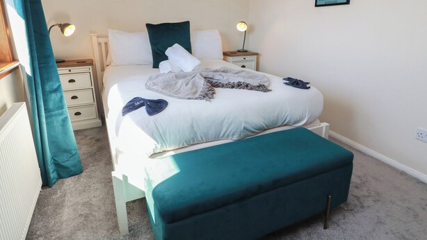 Ein ordentlich eingerichtetes Schlafzimmer mit einem Bett, Nachttischen, einer Bank und Kunstwerken an den Wänden.
