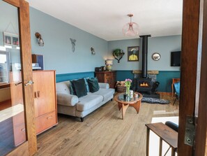 A living room with a sofa, coffee table, fireplace, and decorative wall art. - Crown Cottage (Dunfermline)