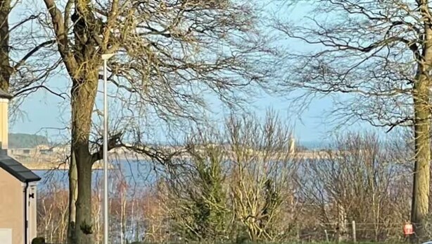 Une voie d’accès privée, signalée par un panneau indiquant qu’elle est réservée aux résidents, mène à un immeuble offrant une vue sur l’eau.