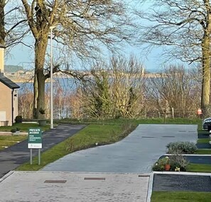 Een privé-oprijlaan met een bord dat aangeeft dat deze alleen voor bewoners is, leidend naar een gebouw met uitzicht op het water.