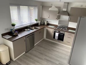 A modern kitchen with a gas stove, stainless steel appliances, a sink, and a window with blinds. - St Andrews Golf Getaway - 3.5 miles to Old Course + Private Putting Green (St Andrews)