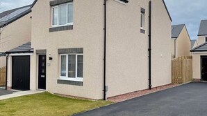 Une maison moderne à deux étages, dotée d’un garage, d’une pelouse bien entretenue et d’une allée pavée.