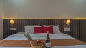 Ein Hotelzimmer mit einem Bett, zwei Wandlampen, einer Obstschale und einer Weinflasche auf dem Bett.