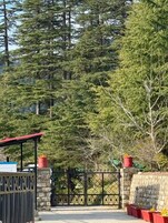 A gated entrance with a stone wall, a metal gate, and a red-roofed structure.