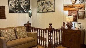 Una sala de estar con un sofá, un tapete estampado, una araña y obras de arte en la pared.
