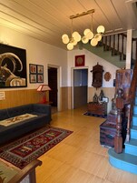 A living room with a blue sofa, a patterned rug, a staircase, and a chandelier.
