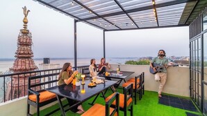 A rooftop terrace with a table, chairs, a guitar player, and a decorative structure.
