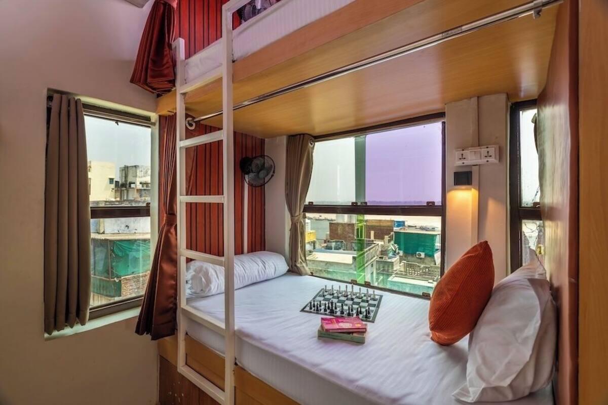 Habitación con literas, ventana y un tablero de ajedrez sobre la cama.