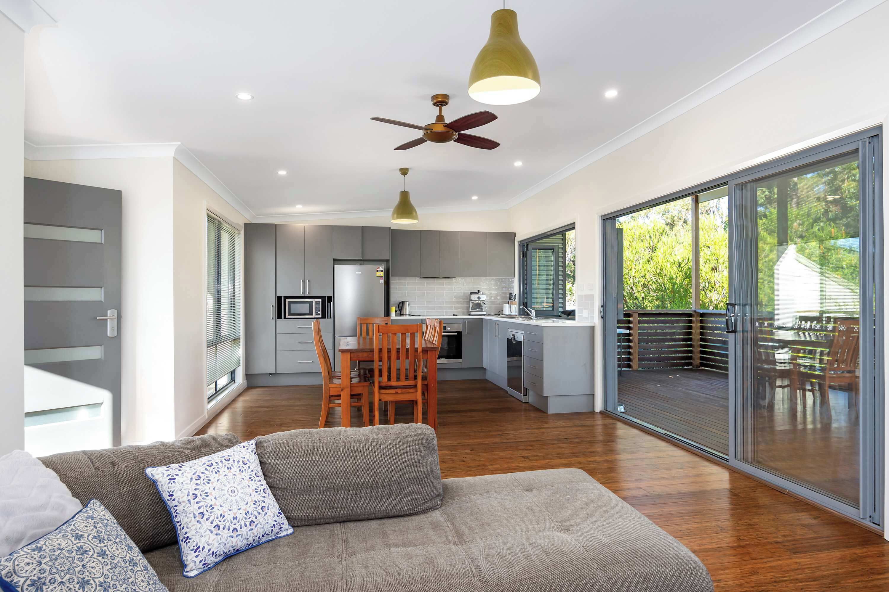 Una cocina moderna con comedor, ventilador de techo y puerta corrediza de vidrio que da a una terraza exterior.