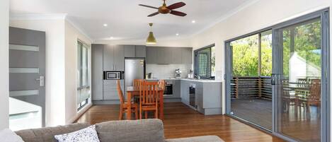 Una cocina moderna con comedor, ventilador de techo y puerta corrediza de vidrio que da a una terraza exterior.
