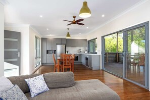 A modern kitchen with a dining area, large sliding glass doors to a deck, and a ceiling fan. - Aloha Kioloa at Kioloa Beach Pet Friendly (Kioloa)