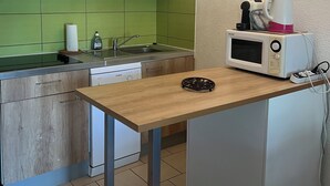 Et kompakt køkken med en træbordplade, en mikrobølgeovn, en vask og en grøn bagplade.