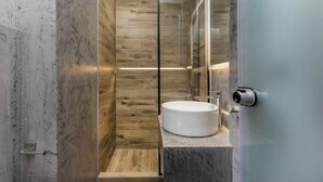 Un baño moderno con pared de madera, encimera de mármol y lavamanos redondo.