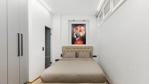 Un dormitorio con cama, armario y un cuadro en la pared.