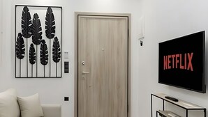 Una sala de estar moderna con un sofá, un televisor, una obra de arte en la pared y una puerta de madera.