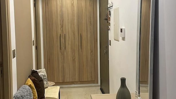 Un corridoio con un'armadietto in legno, uno specchio, un vaso e un tavolino.