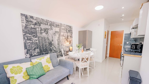 A modern living room with a sofa, dining table, and kitchen area. - Town Centre Gem Bright and Spacious 3-Bed (Cardiff)