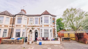 A two-story house with a bay window, a front door, and a small front garden. - Town Centre Gem Bright and Spacious 3-Bed (Cardiff)