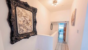 A hallway with a white wall, a black ornate mirror, and a white counter. - Town Centre Gem Bright and Spacious 3-Bed (Cardiff)