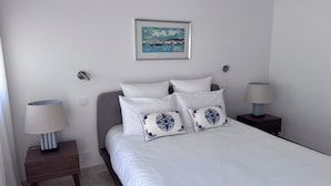 A neatly arranged bedroom with a bed, two bedside tables, a lamp, and a framed picture on the wall.