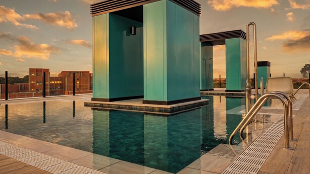 A modern pool area with clear water, metal railings, and a sunset view.