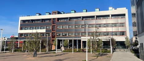 Un edificio de varios pisos con un diseño arquitectónico moderno, que cuenta con un atrio central y una zona exterior cubierta.