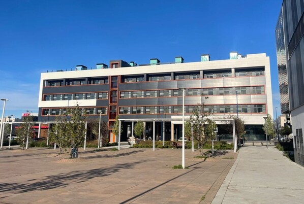 A multi-story building with a modern architectural design, featuring a central atrium and a covered outdoor area.