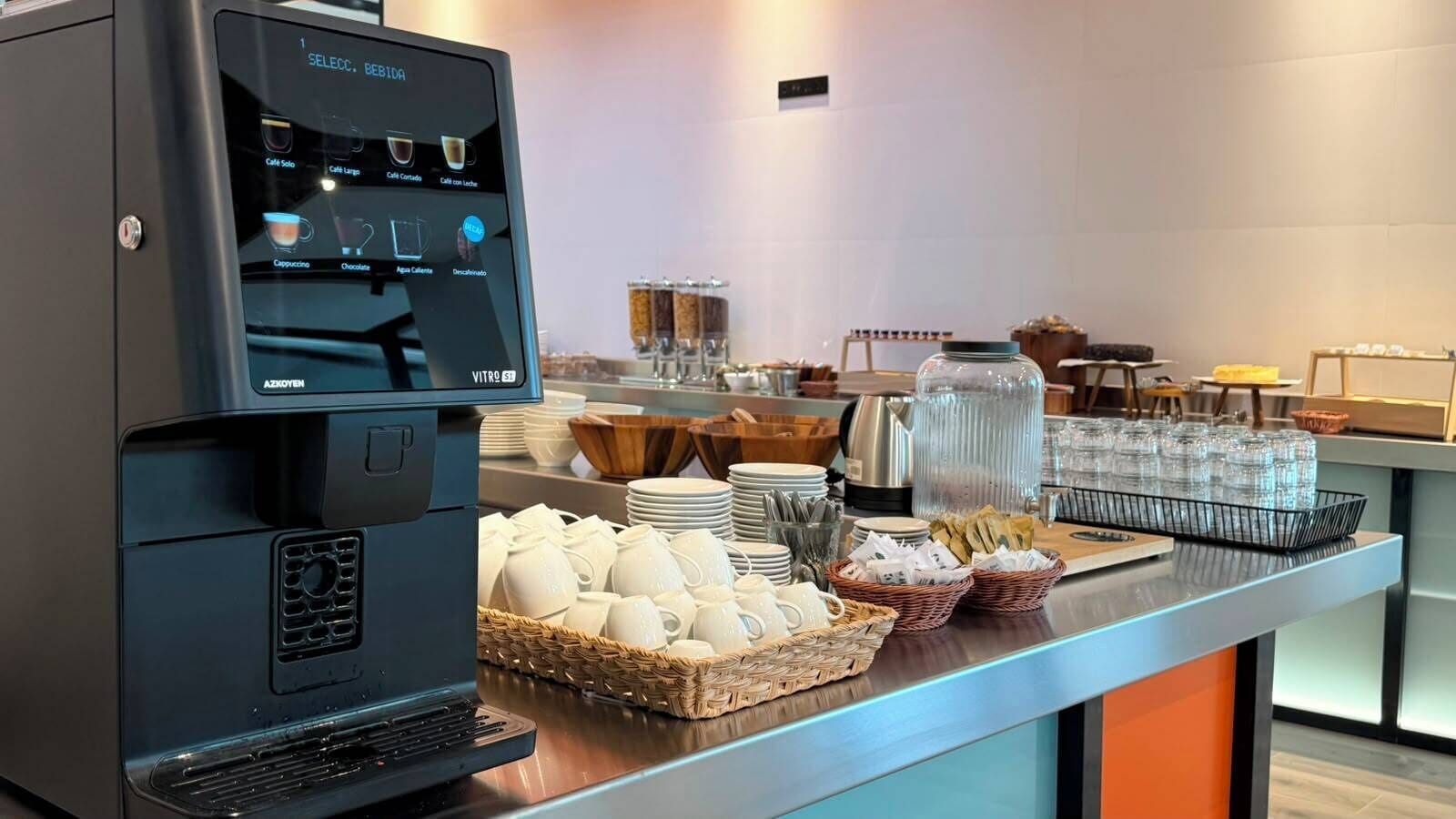 A coffee station with a coffee machine, cups, and a variety of coffee options.