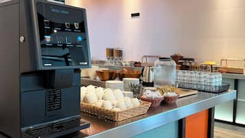 A coffee station with a coffee machine, cups, and a variety of coffee options.