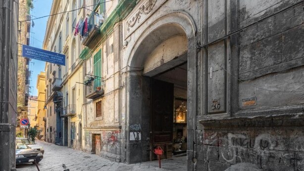 Eine schmale Straße mit historischen Gebäuden, einem Schild für ein staatliches Museum und einem geschlossenen Geschäft.