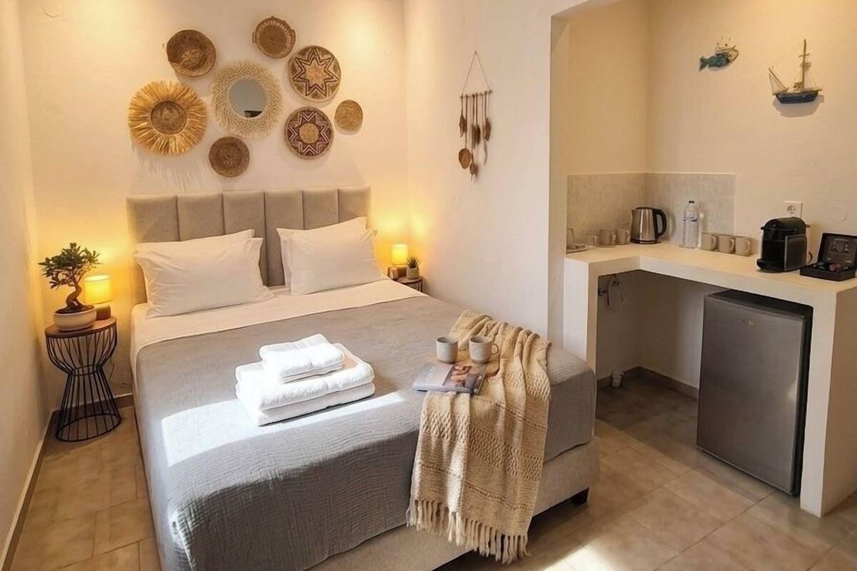 Una habitación de hotel moderna con cama, mesitas de noche, escritorio y kitchenette.