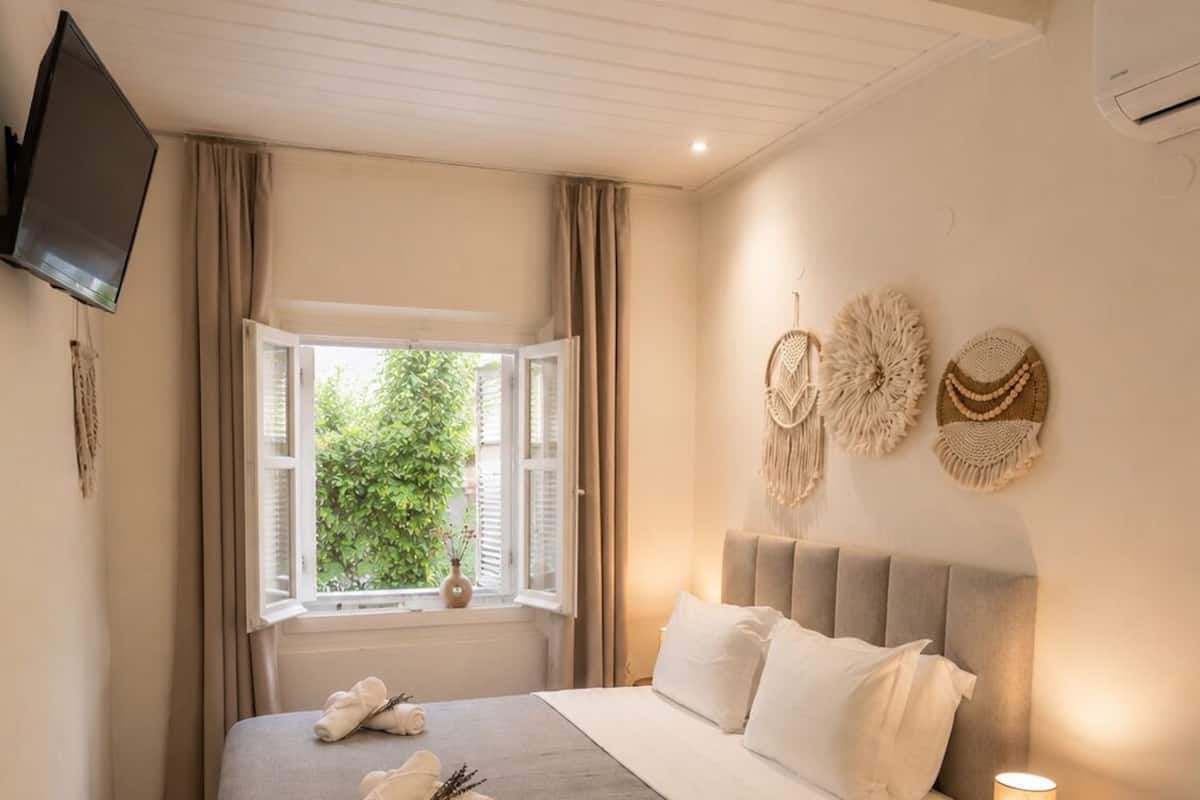 Un dormitorio con cama, lámpara de noche, ventana con cortinas y decoración en la pared.