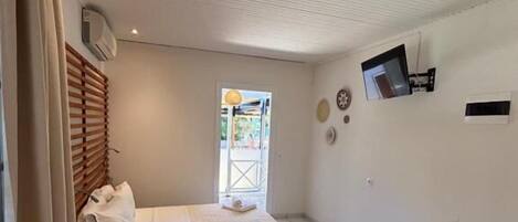 A small, clean room with a bed, a TV, and a window.