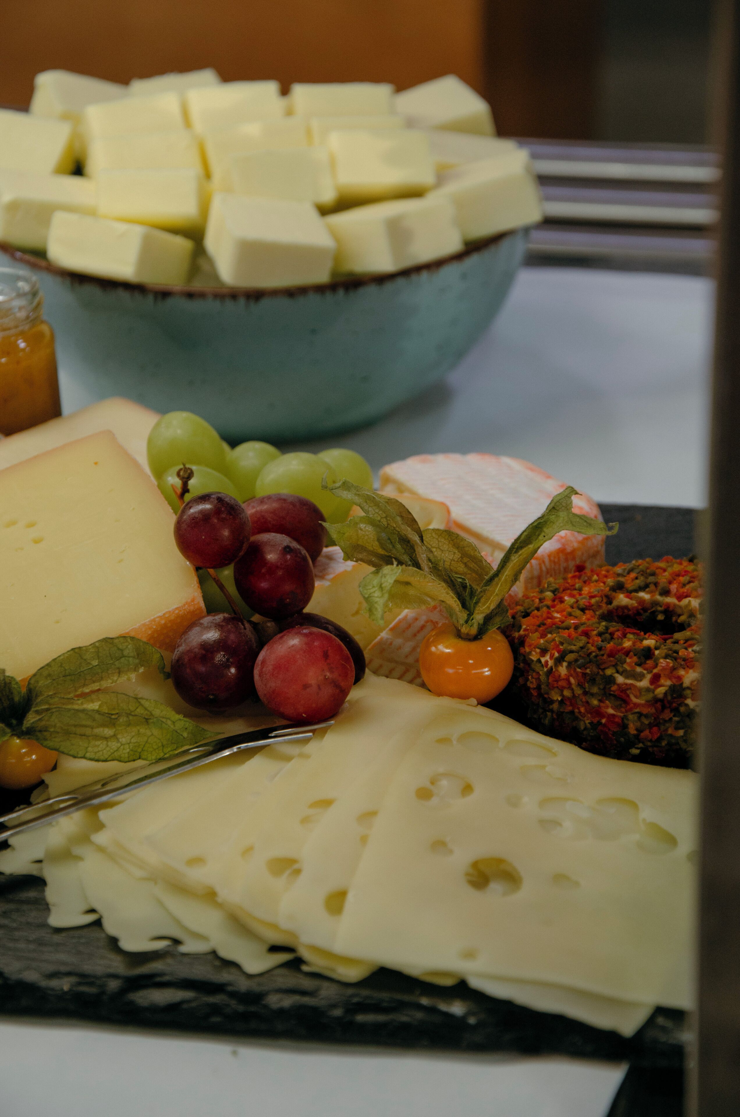 Un plateau de fromages comprenant différents types de fromages, des raisins et un objet décoratif.