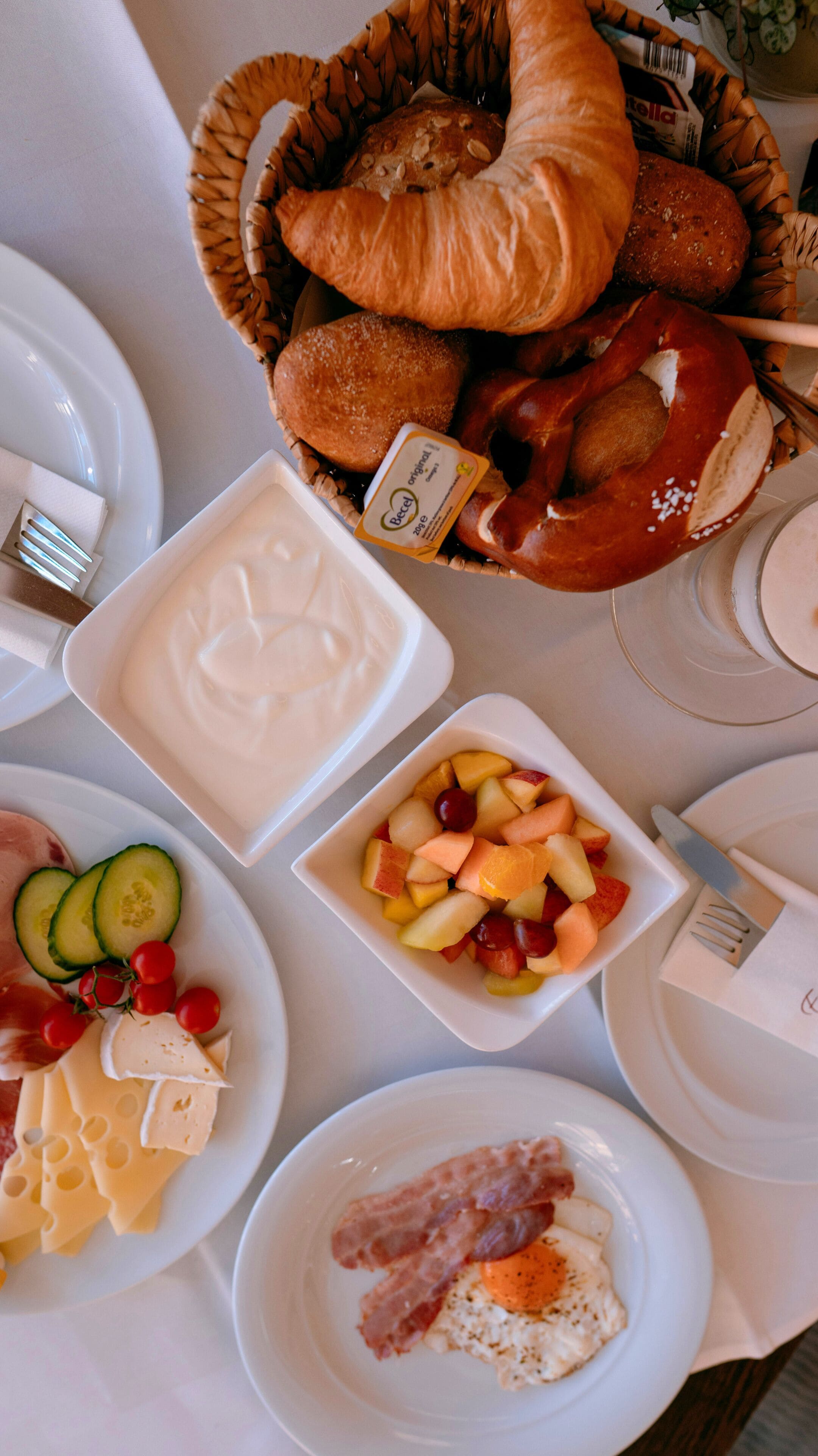 A breakfast buffet with bread, cheese, fruit, and eggs.