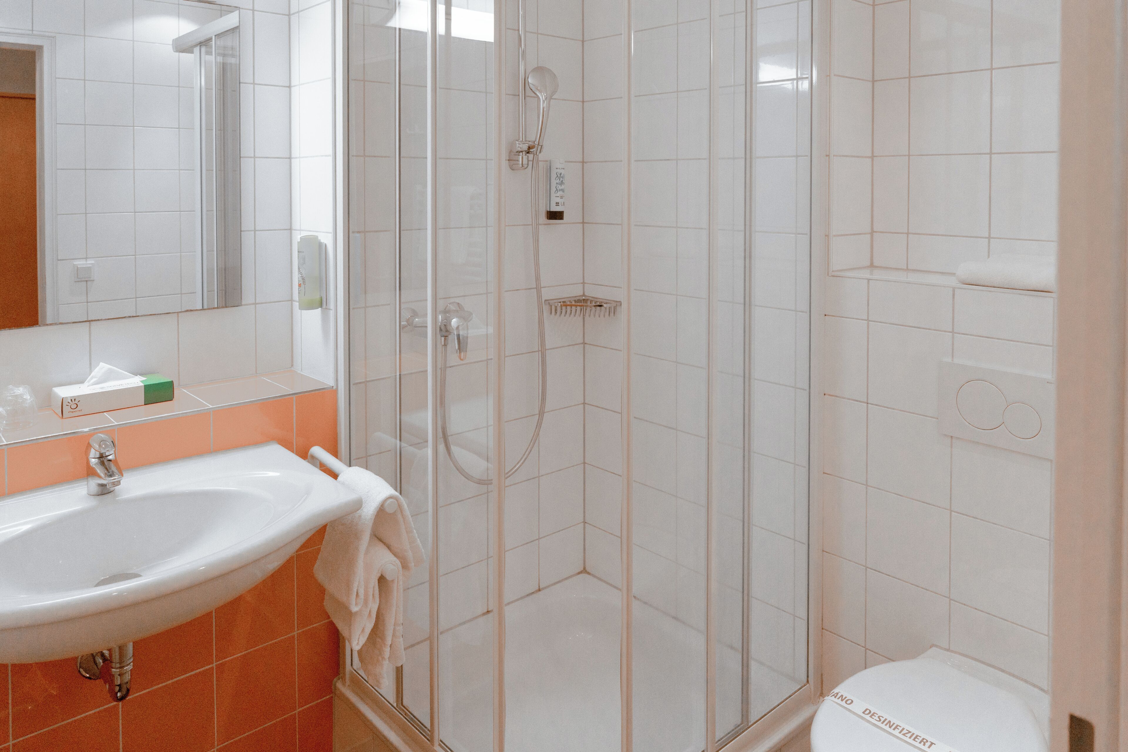 A bathroom with a glass-enclosed shower, a sink with a towel, and a toilet.
