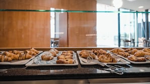 Mostrador de buffet con diversos pasteles y una mampara de vidrio.