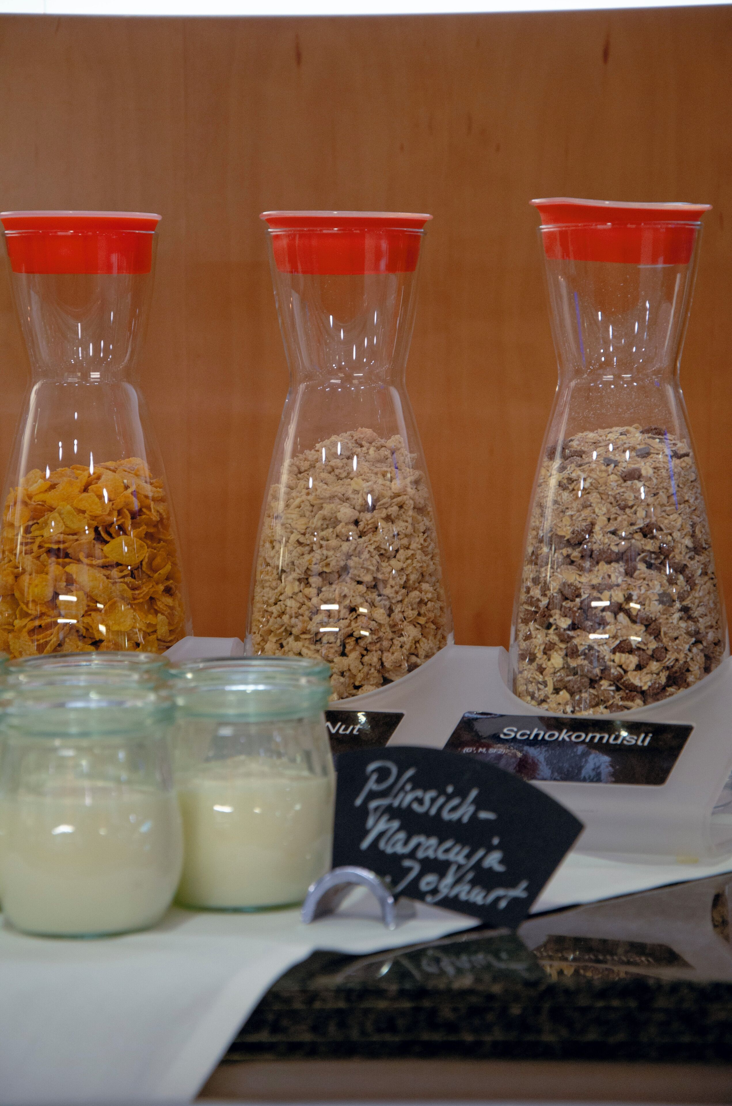 Três recipientes de vidro com diferentes tipos de cereal e dois potes de vidro com uma substância branca.