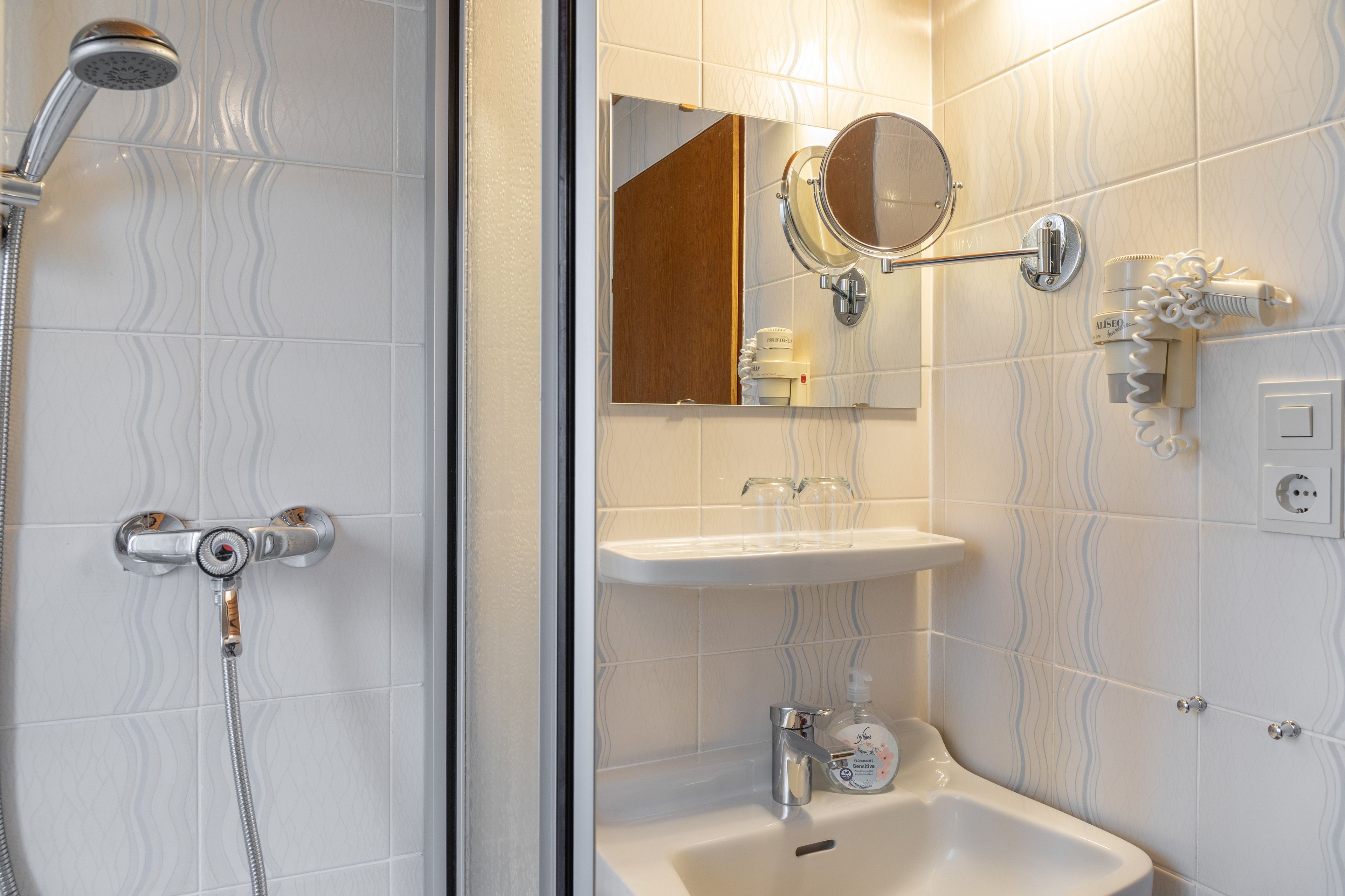 Ein Badezimmer mit Dusche, Waschbecken und Spiegel.