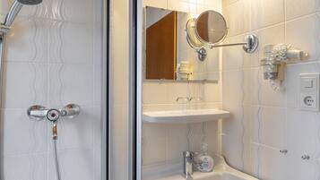 Ein Badezimmer mit Dusche, Waschbecken und Spiegel.