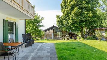 A patio with outdoor furniture, a wooden deck, and a grassy area with trees.
