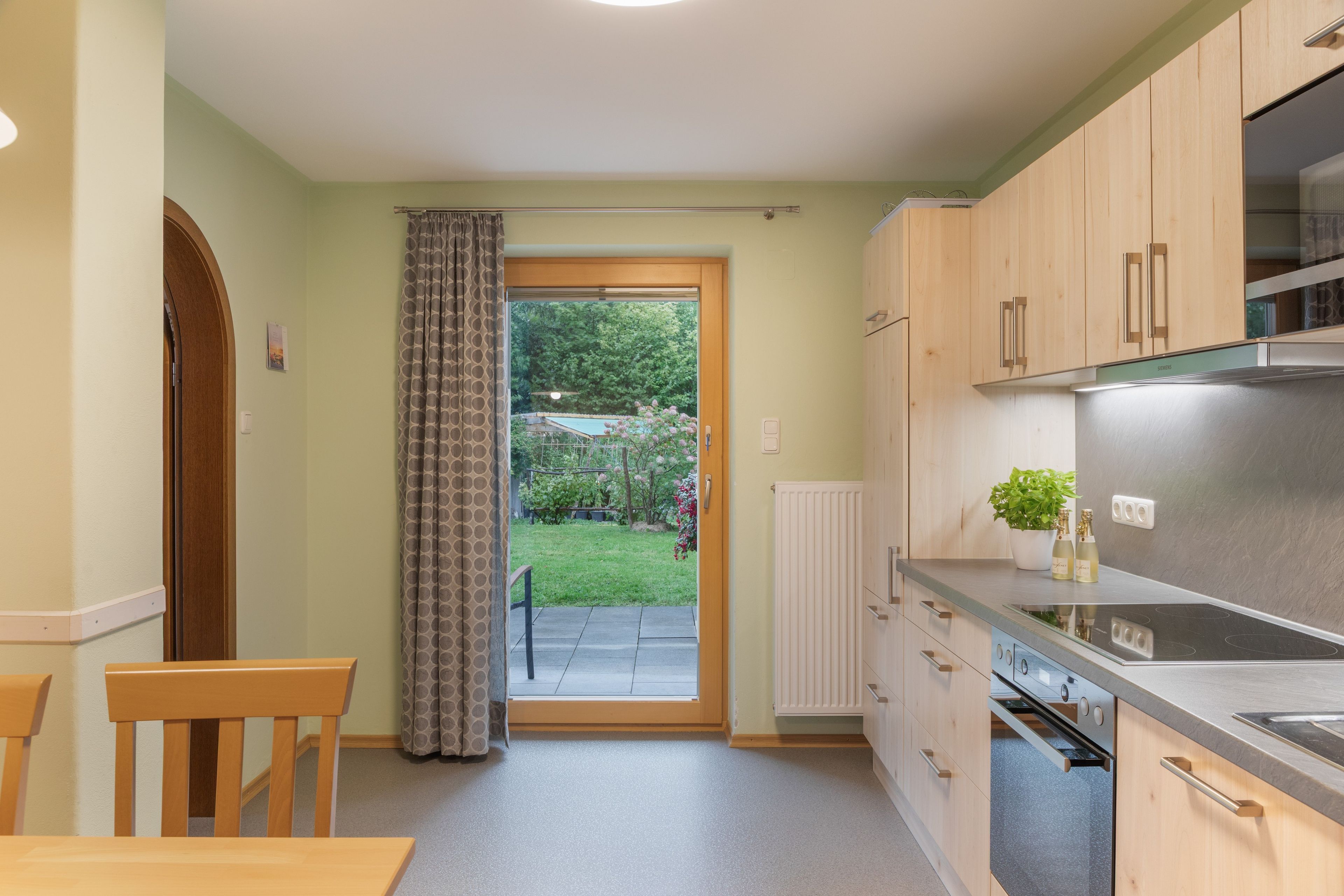 Eine Küche mit Holzausstattung, einem Edelstahlkühlschrank und einem Essbereich mit Tisch und Stühlen.
